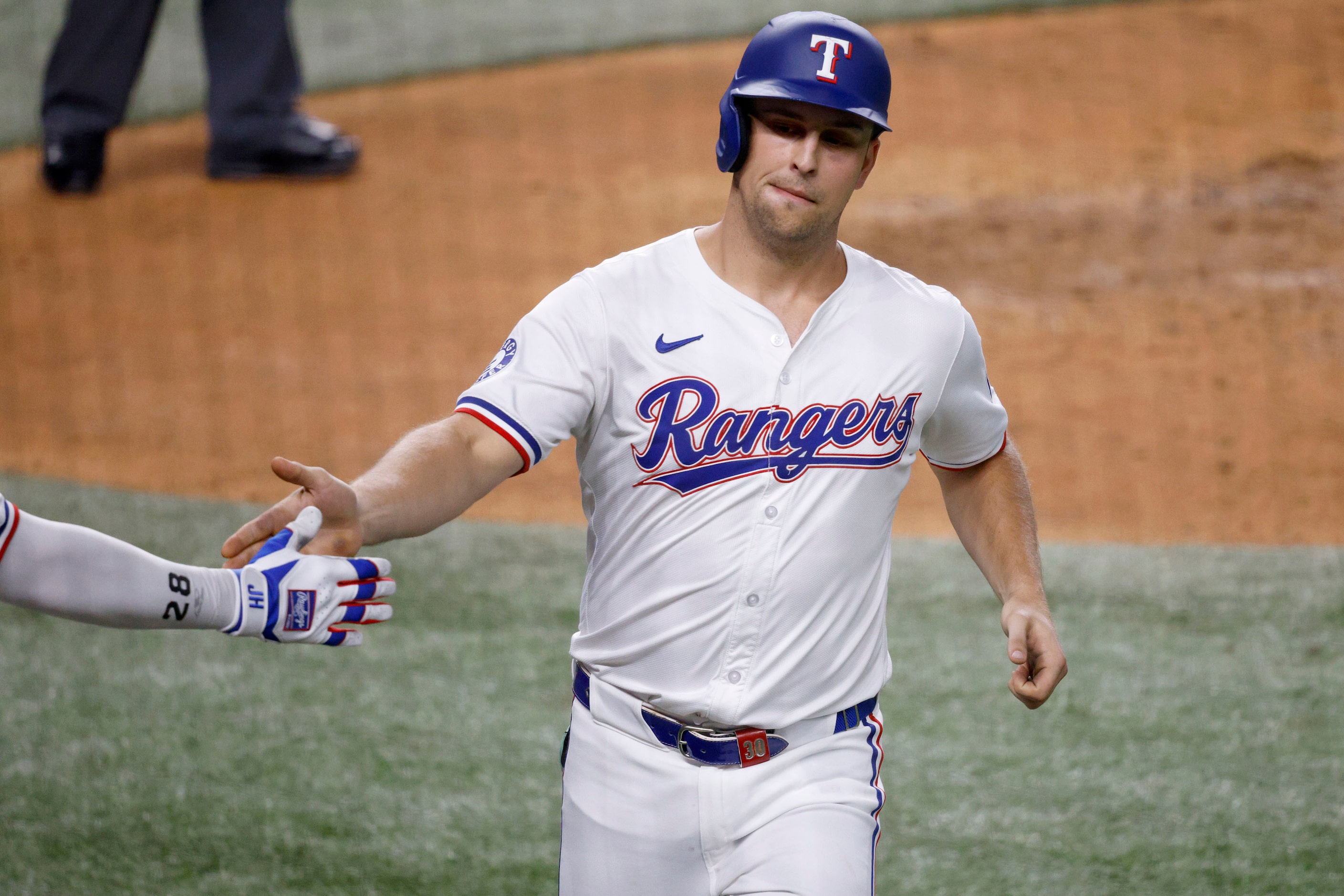 Texas Rangers’ Nathaniel Lowe (30) gets a high-five from his teammate after scoring on a...