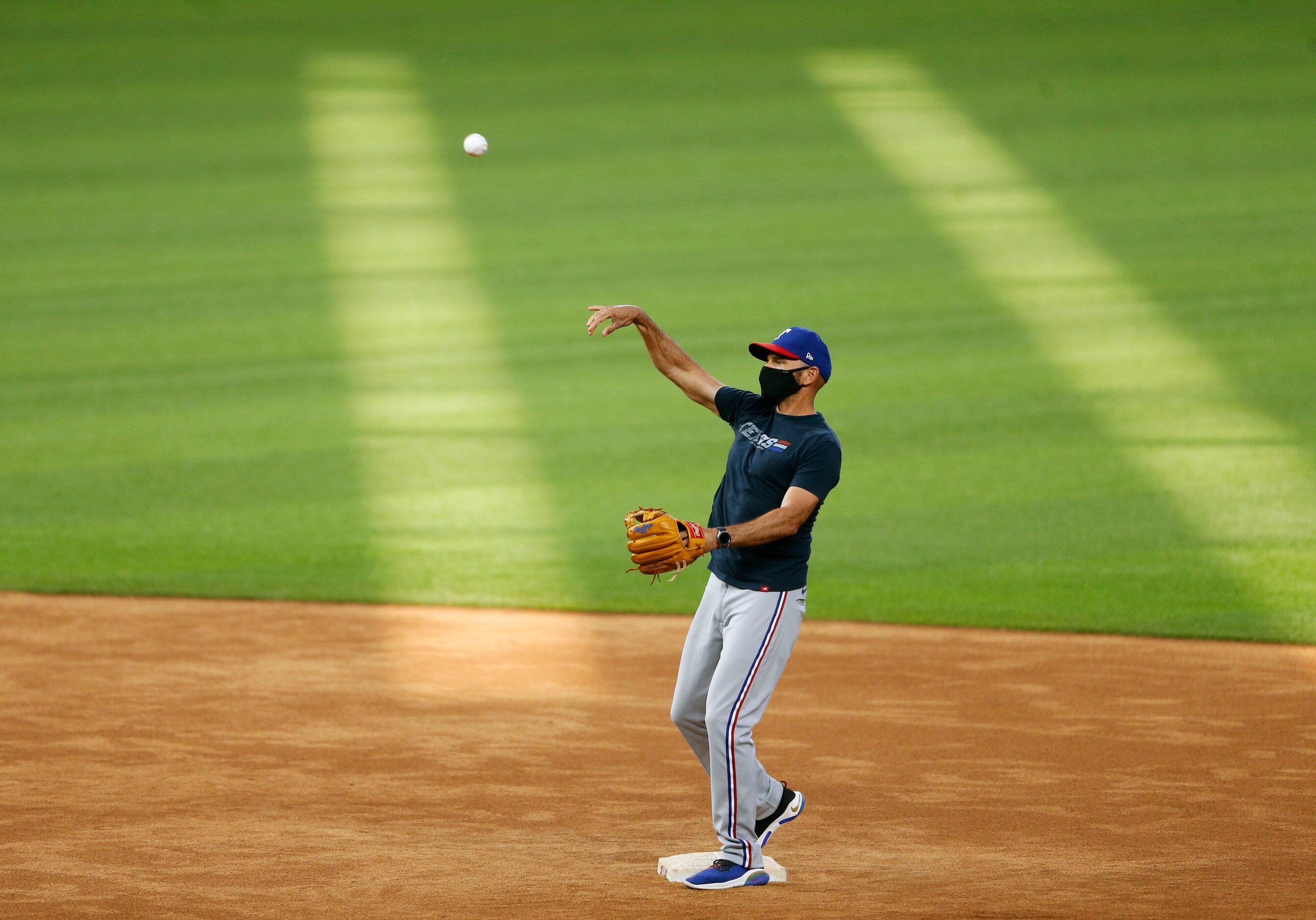 Texas Rangers manager Chris Woodward throws the ball during batting practice at Texas...