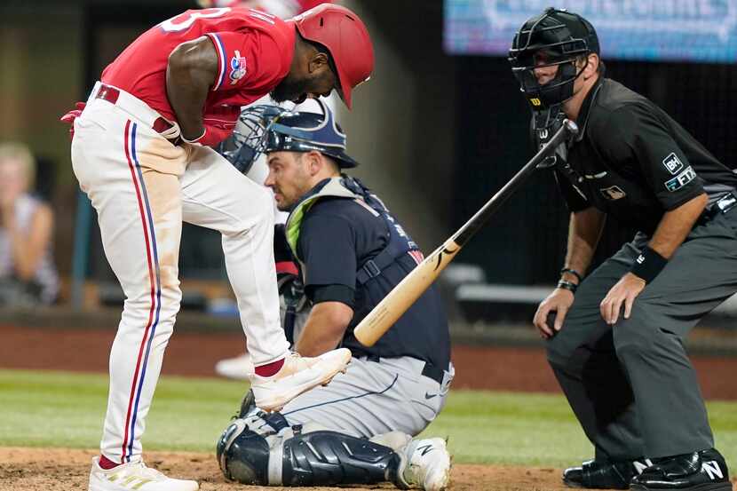 Texas Rangers' Adolis Garcia, left, reacts after getting hit by a pitch on the hand in front...