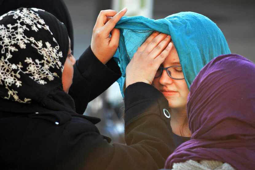 A Muslim student, left, helps Sarah Pooley, 14, of Albuquerque, try on the traditional head...