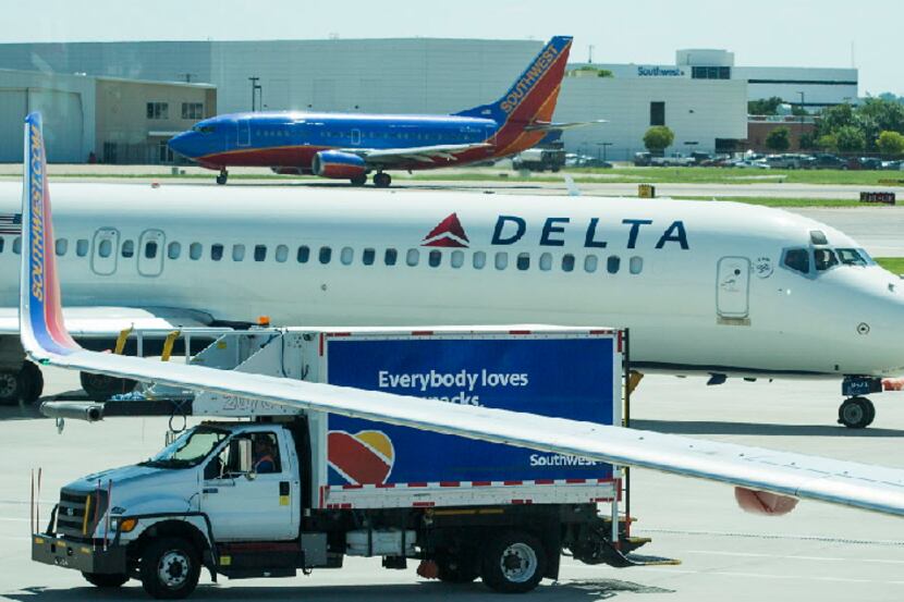A Delta Air Lines jet taxis between two Southwest Airlines jets at Dallas Love Field....