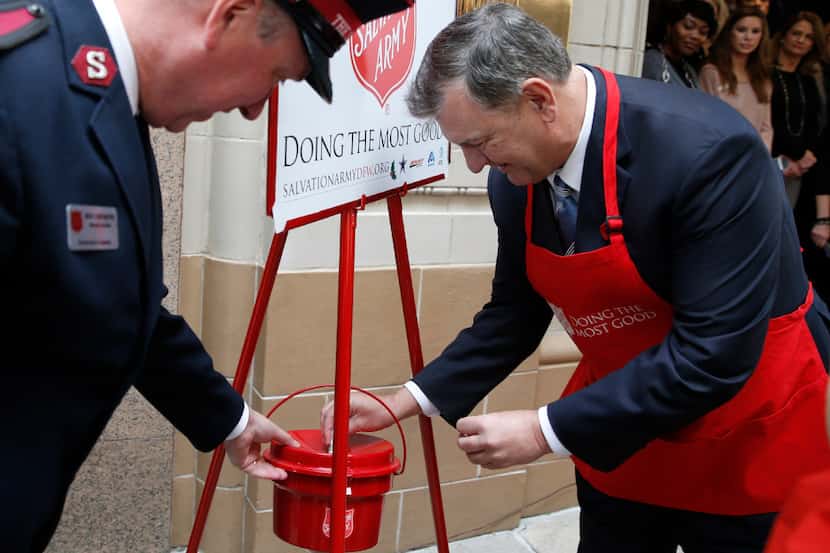 Metroplex Commander Major Jonathan Rich (left) watches as Mayor Mike Rawlings puts a dollar...