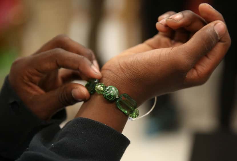 Sixth-grader Isaiah Blakely tries on a bracelet in the Unity Bracelets Club at Oliver W....