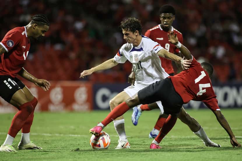United States' Brenden Aaronson, center, fights for the ball with Trinidad and Tobago's...