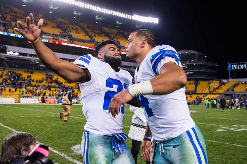 Dallas Cowboys running back Ezekiel Elliott (21) hugs quarterback Dak Prescott (4) after...