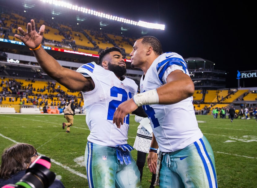 Dallas Cowboys running back Ezekiel Elliott (21) hugs quarterback Dak Prescott (4) after...