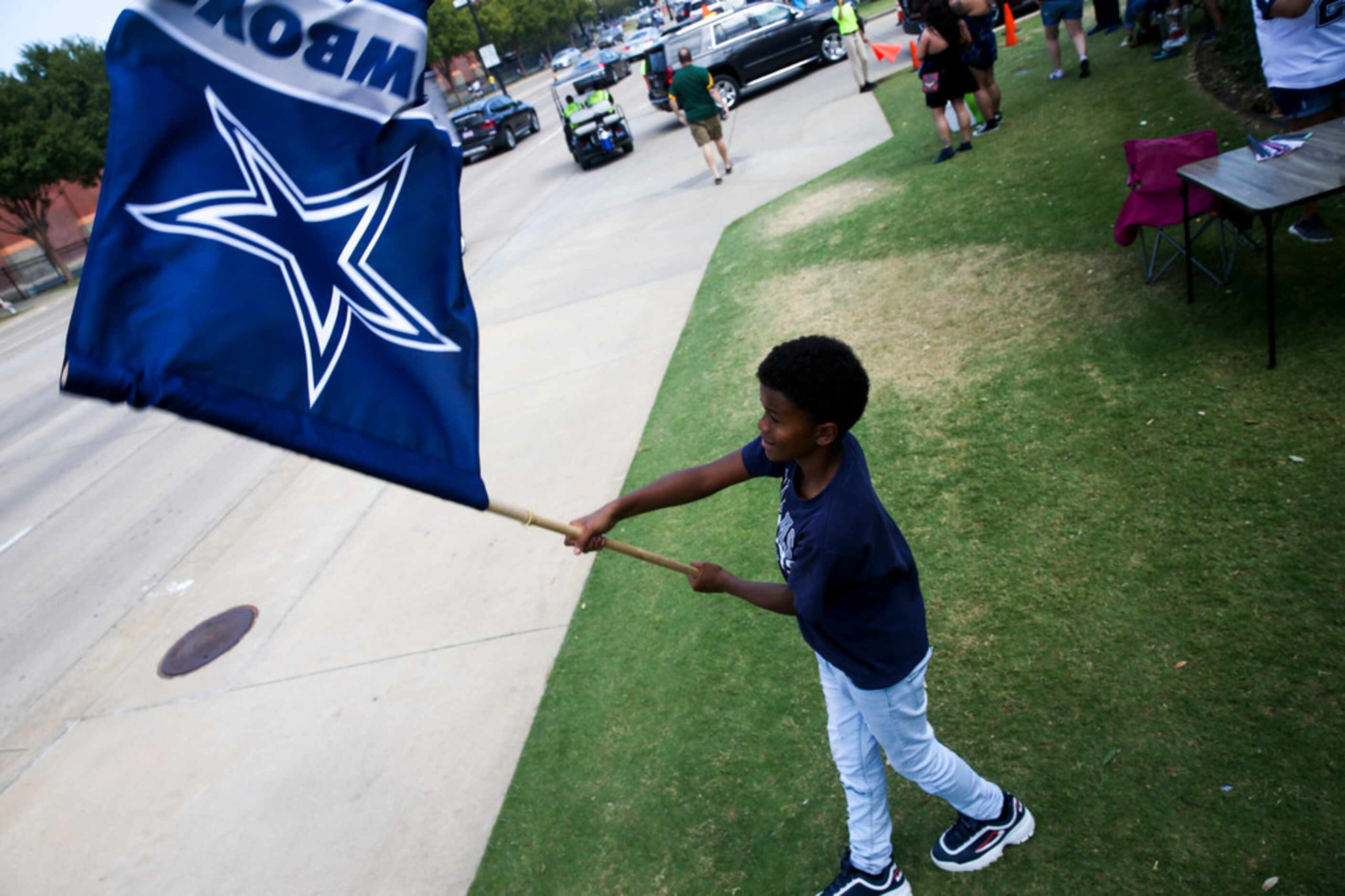 Chandler Robins, 12, waives his Dallas Cowboys flag in the parking lot before an NFL game...