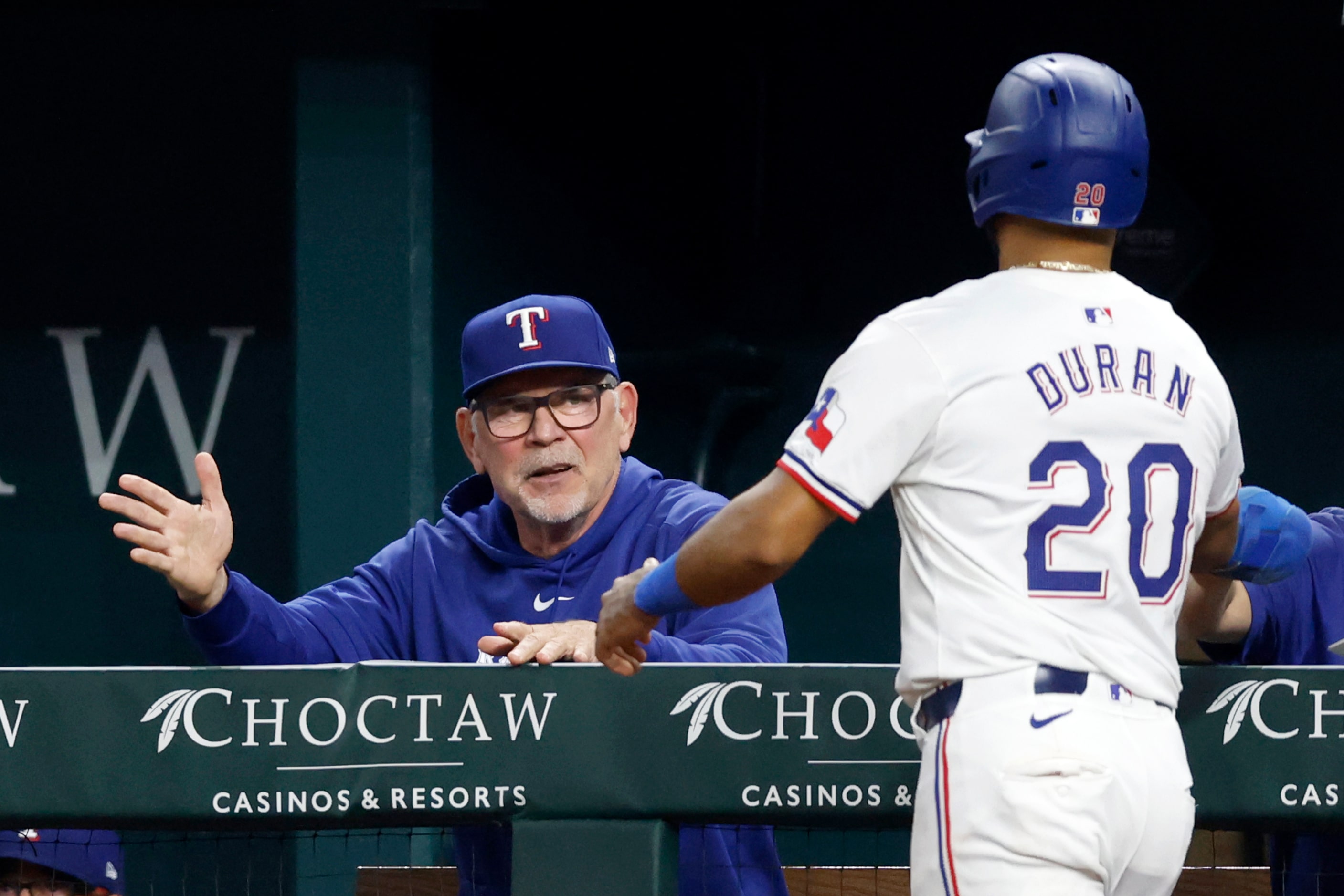 Texas Rangers third baseman Ezequiel Duran (20) high fives manager Bruce Bochy after scoring...