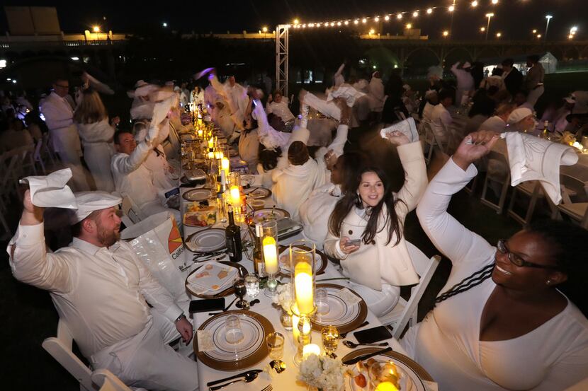 Guests twirl their napkins during a secret Diner en Blanc event at Reunion Park in Dallas on...