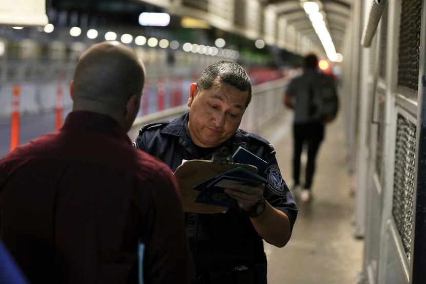 A U.S. Customs and Border Protection officer checks the documents of migrants who are on...