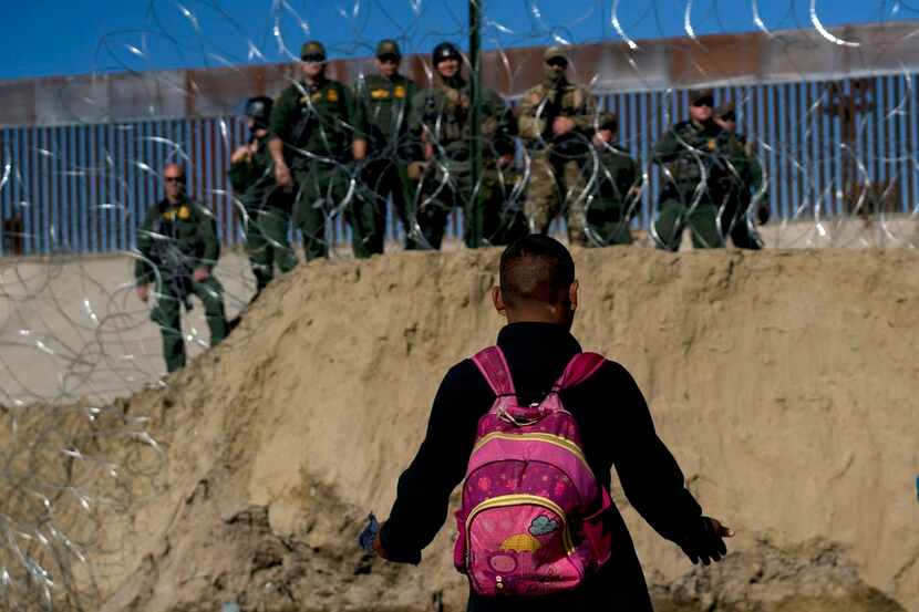 Un migrante hondureño conversa con agentes fronterizos de Estados Unidos del otro lado de un...