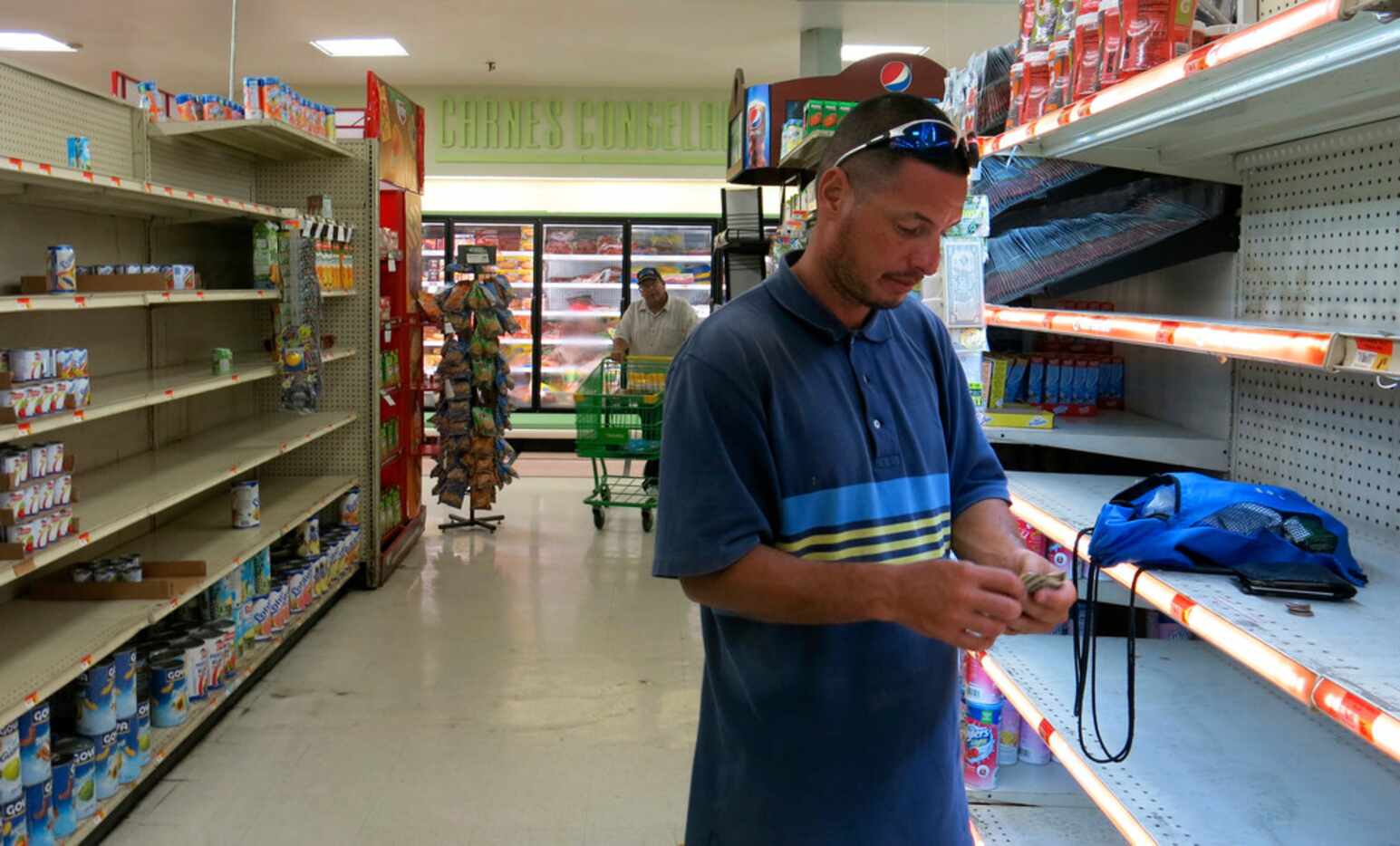Christian Mendoza counts money in the aisle of a supermarket where he had hoped to buy...