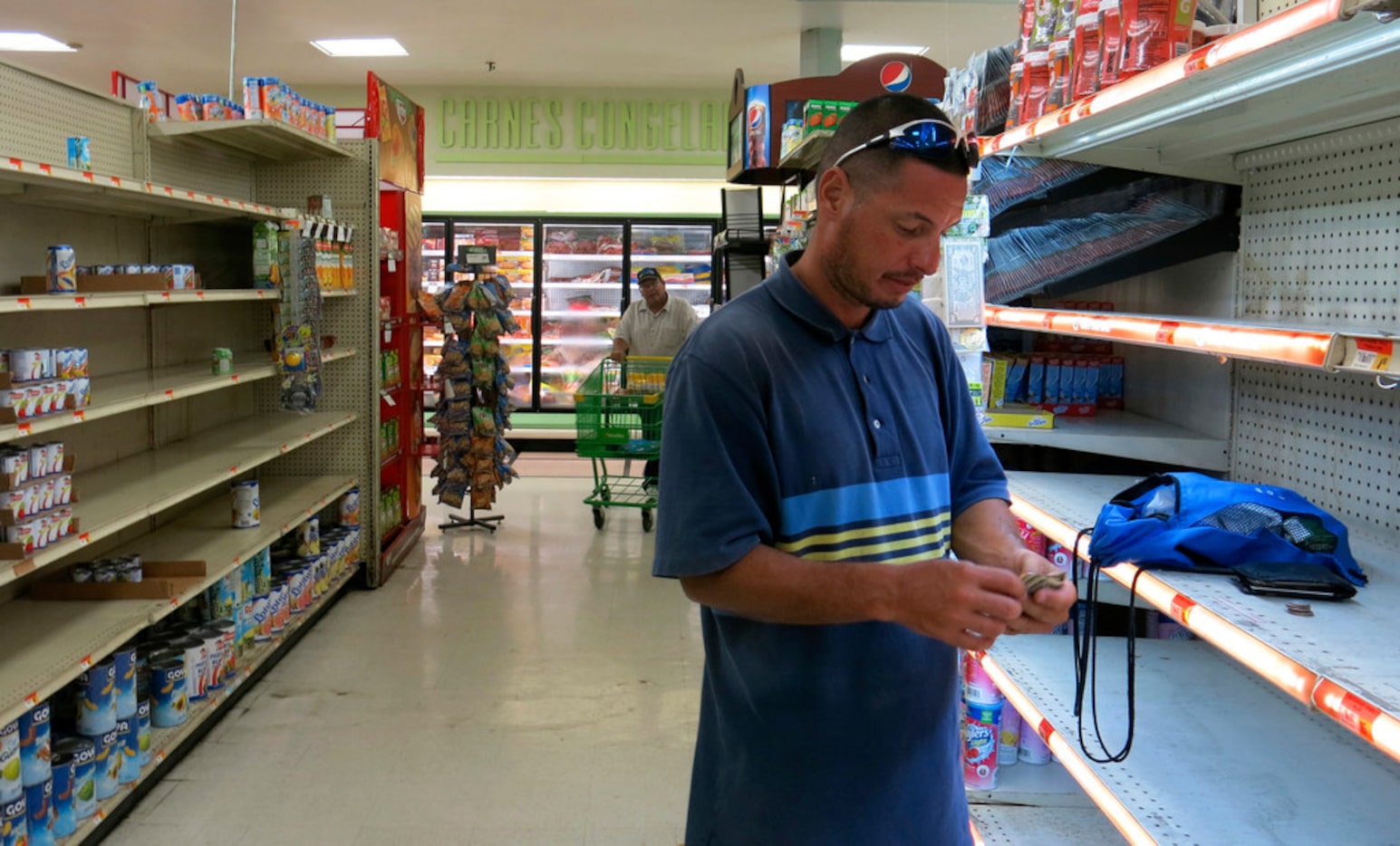 Christian Mendoza counts money in the aisle of a supermarket where he had hoped to buy...