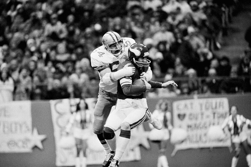 Randy White (54) Dallas Cowboys tackle, wraps his arms around Minnesota Vikings Quarterback...