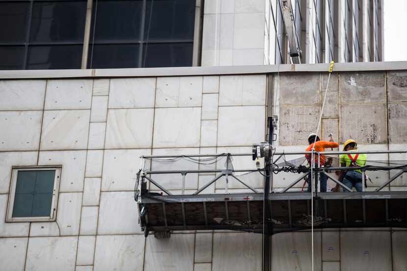 Workers remove panels of marble off of the former First National Bank Tower in downtown...