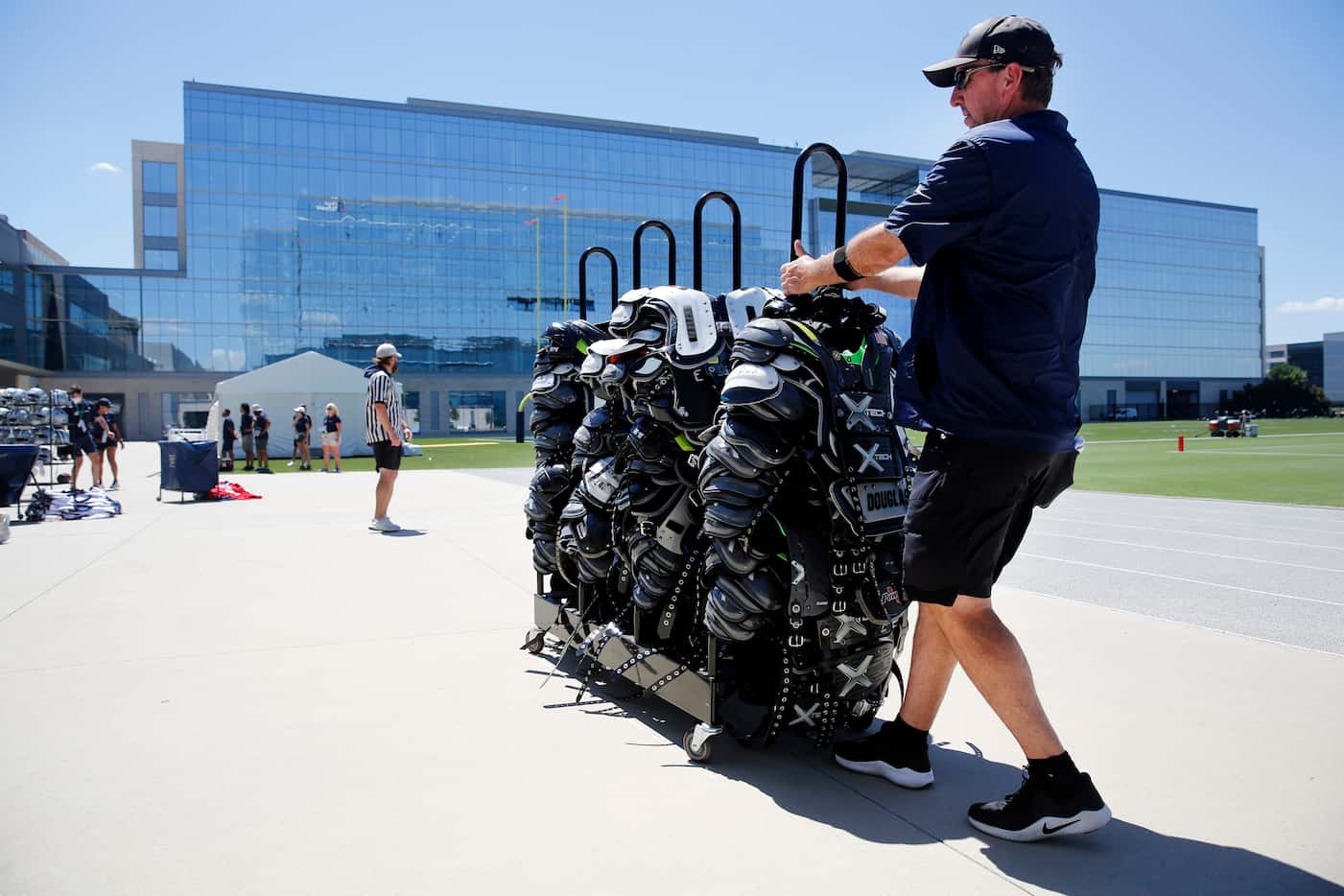 Dallas Cowboys equipment manager Mike McCord pulls a rack of shoulder pads after players...
