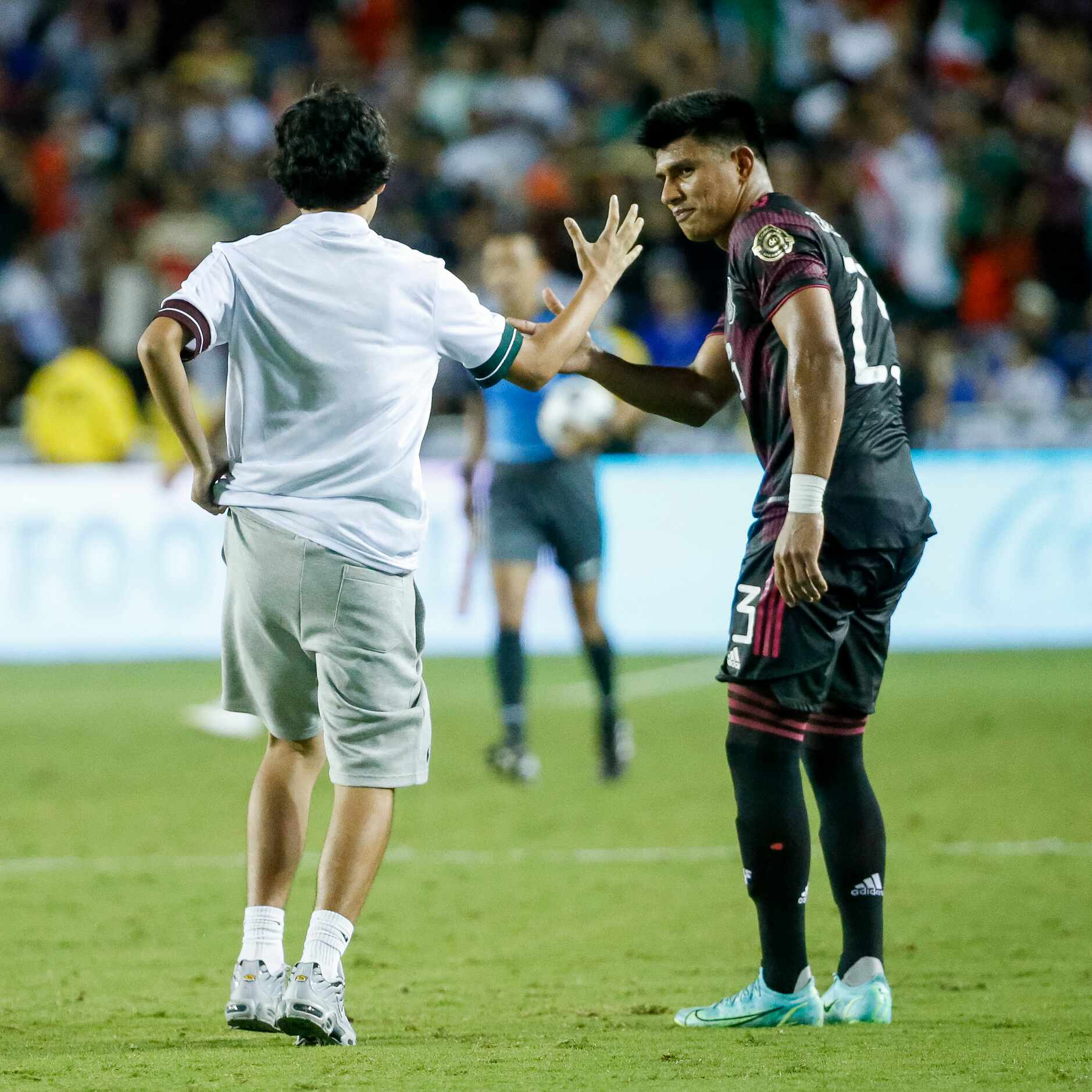 A fan on the field high-fives Mexico midfielder Jesús Gallardo (23) after a CONCACAF Gold...