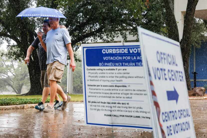 Dallas residents James Kleitches, left, and Les Nini shares an umbrella as they exit the...