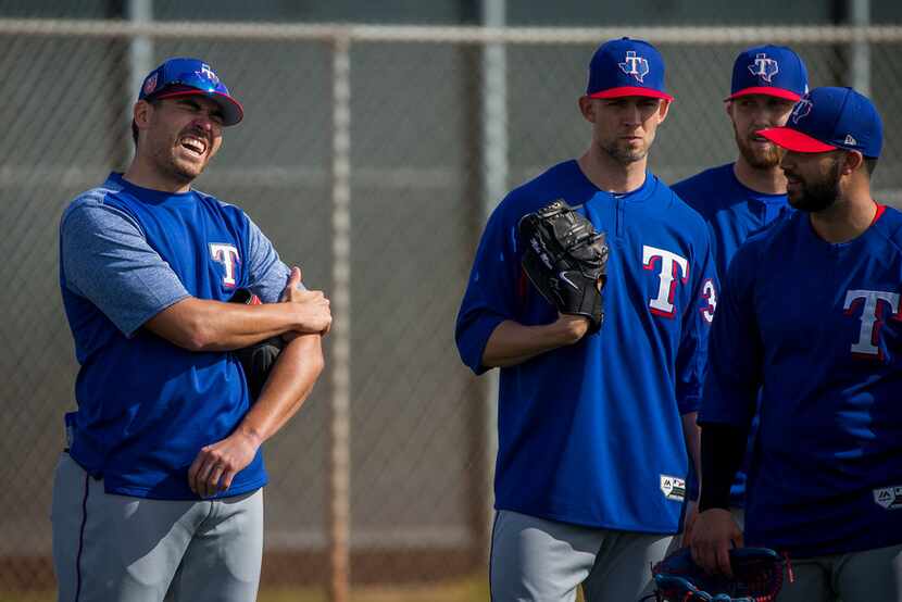 Texas Rangers pitcher Matt Moore grabs his arm as he talks with Mike Minor and Matt Bush...