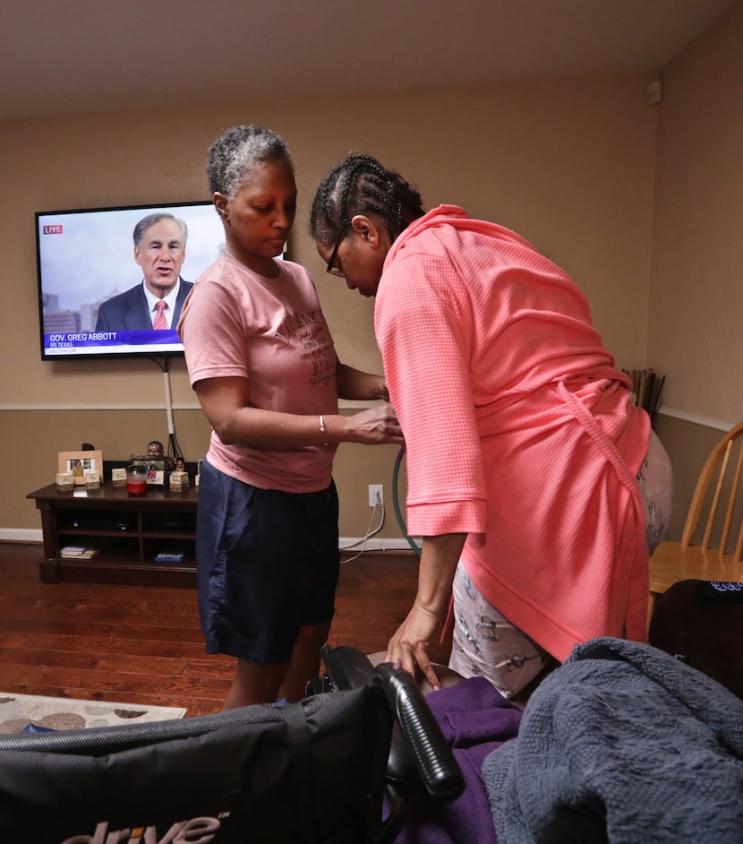 Bea Brown (left) assists her sister Beth in moving between her wheelchair and a chair at...