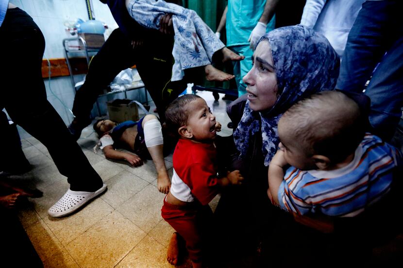 A Palestinian medic holds two children, wounded during fighting between Israeli forces and...