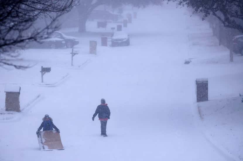 Kids improvised by sledding on large pieces of cardboard down a steep, snow-covered street...