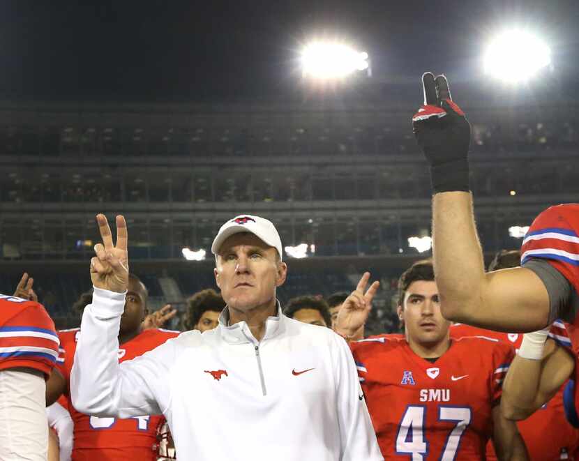 SMU head coach Chad Morris stands with his players as the school song is played following...