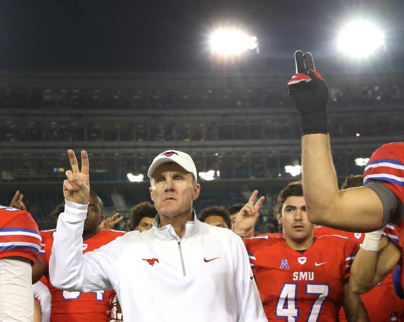 SMU head coach Chad Morris stands with his players as the school song is played following...