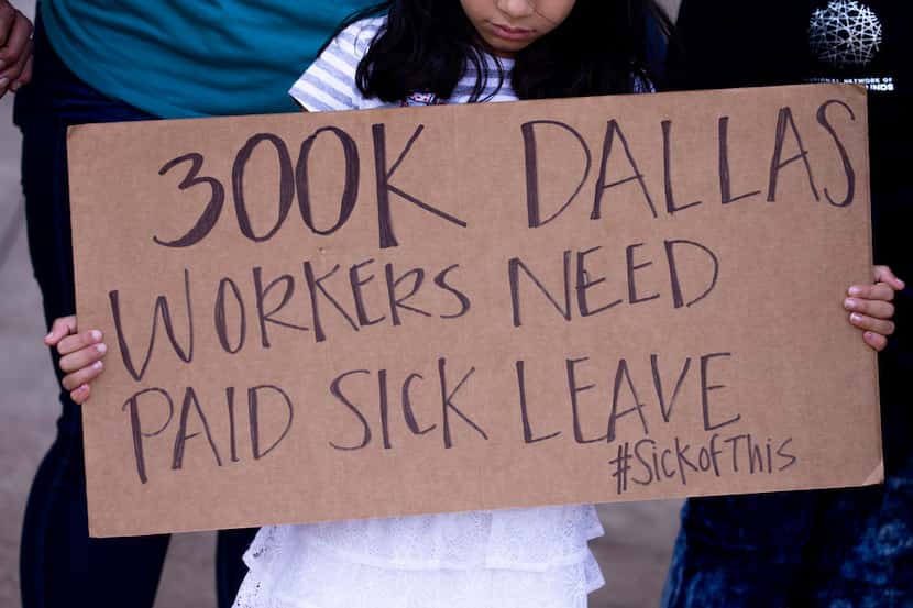A  girl holds a sign during during a press conference about a paid sick time ordinance...