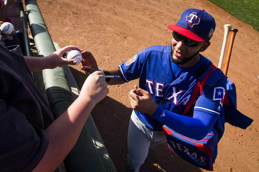 Texas Rangers outfielder Nomar Mazara signs autographs for fans after a spring game against...