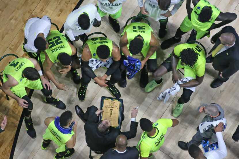 The Baylor team listens intently as head coach Scott Drew draws up a play during a time out...