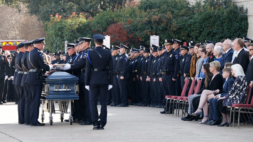 Members of the Mesquite Police Honor Guard fold the flag that was draped across Houston's...