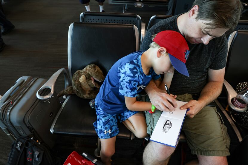 Sam Smith, 6, and his father Josh draw a car together while waiting during a four hour delay...