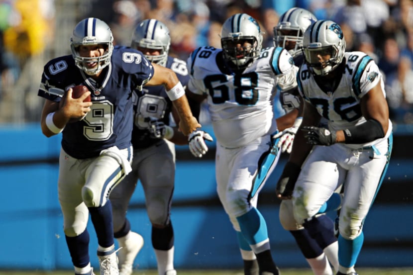Dallas Cowboys quarterback Tony Romo (9) stays ahead of Carolina Panthers defenders on a...