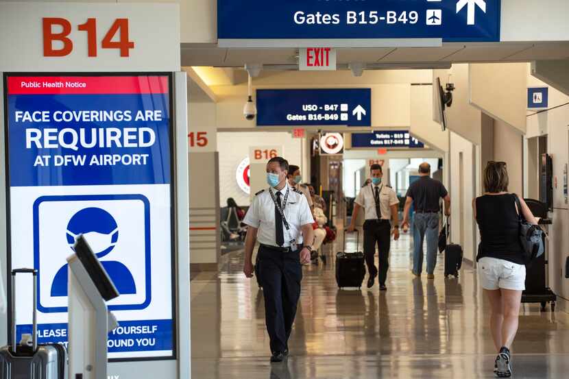 Pilots walk by signage informing travelers to stop the spread of covid-19  in Terminal B at...