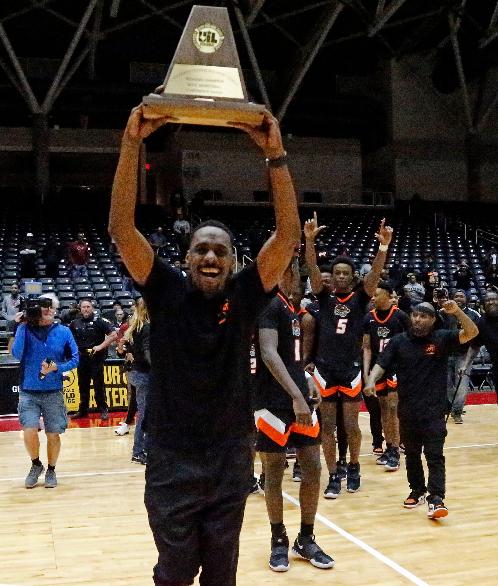 Lancaster High School head coach Ferrin Douglas hoists up the trophy after the win as...