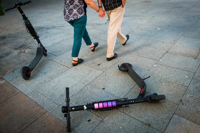 A Lyft scooter lies on a sidewalk along Commerce Street in downtown Dallas.