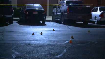 Investigators mark the area where three men were wounded by gunfire in a confrontation...
