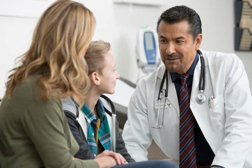 A mother and child speak with a doctor in a doctor's office.