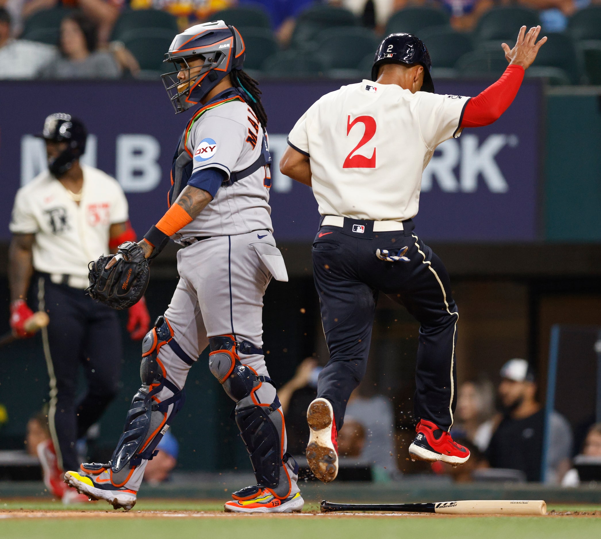 Texas Rangers second baseman Marcus Semien (2) jumps over a bat as he scores a run during...