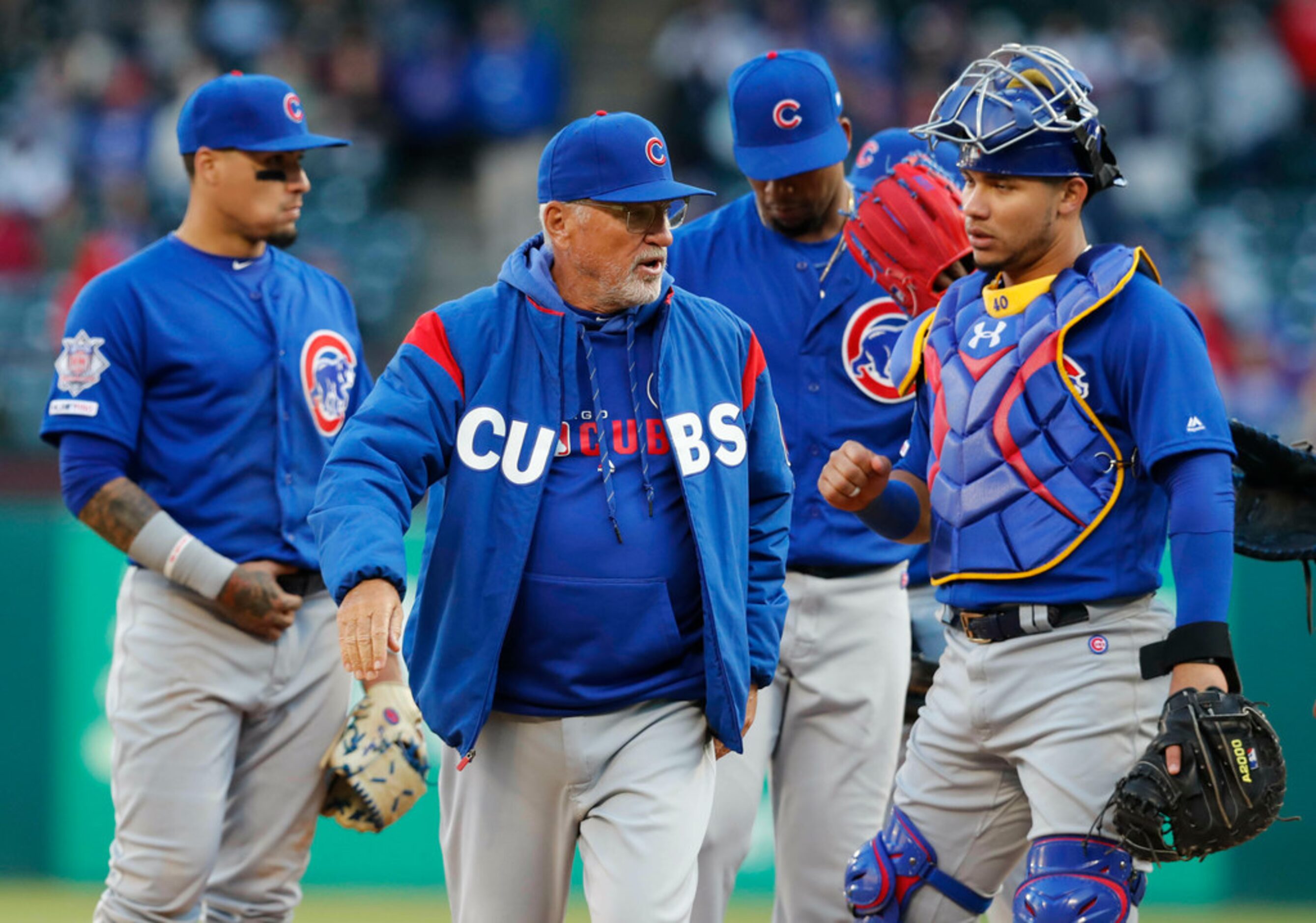 Chicago Cubs manager Joe Maddon, center, heads back to the dugout after a visit to the mound...