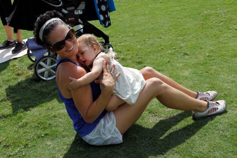 
Lara Neri hugs her daughter, Thea Neri, 11 months, while exercising during a Stroller Boot...