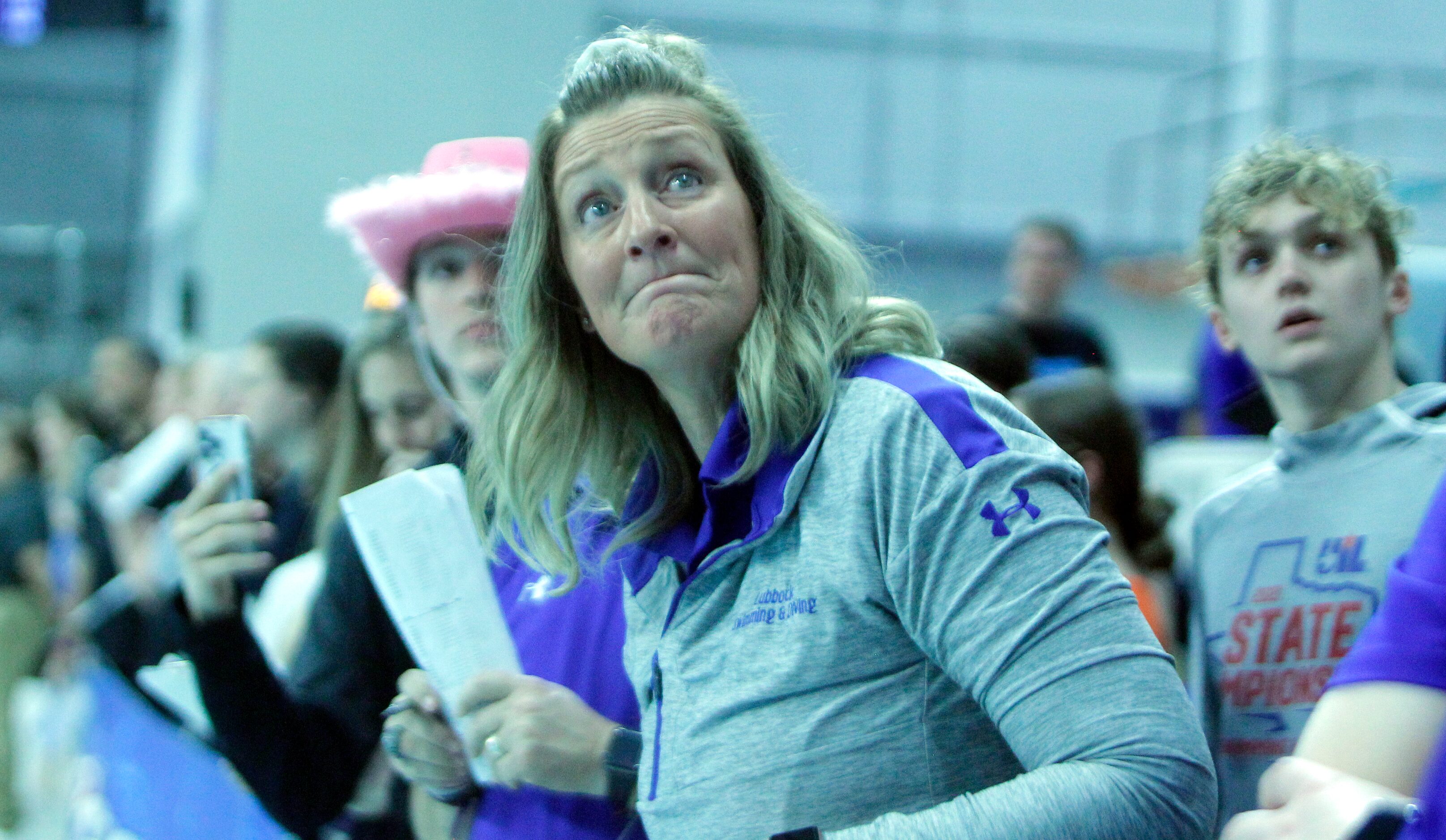 A swim enthusiast at poolside anxiously awaits an update on the leaderboard following a 5A...