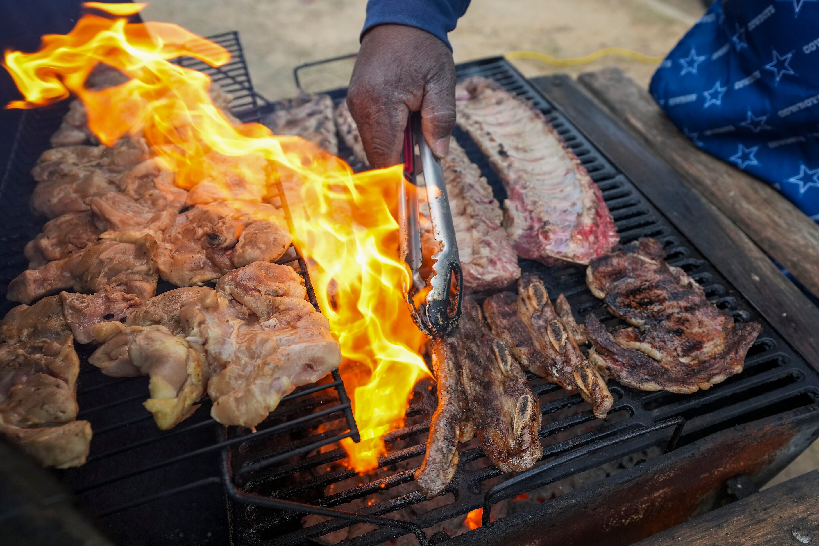 Dallas Cowboys fan Gary Smiley turns ribs on the grill while tailgating before an NFL...