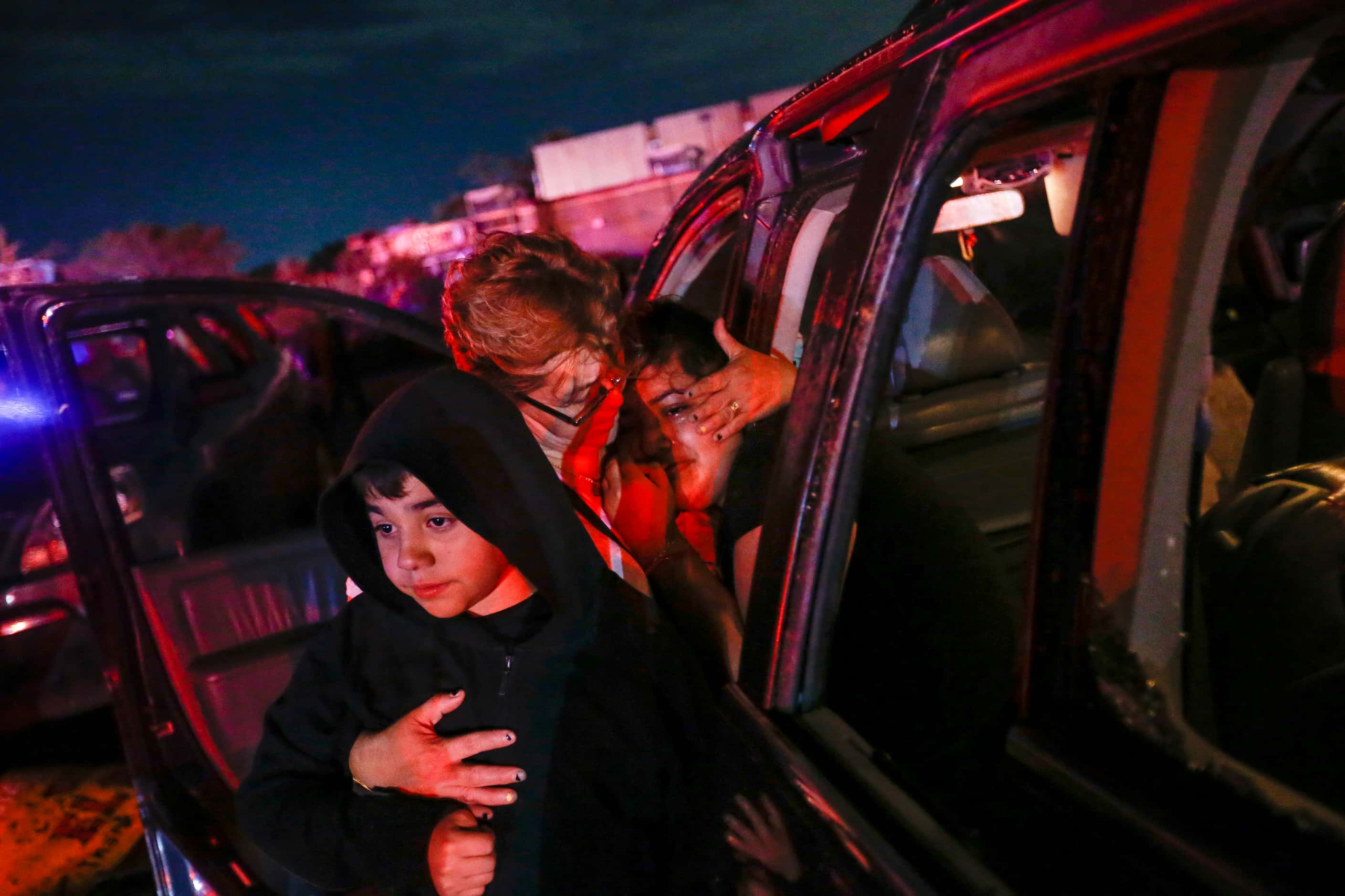 Araceli Estrada, center, embraces Laura Molina, 13, right, and Kevin Molina, 10, left, near...