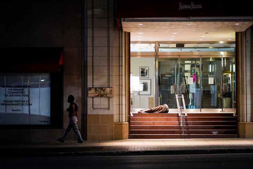 A homeless man sleeps in the doorway of the Neiman Marcus flagship store in downtown Dallas...