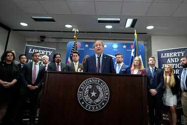 Texas state Attorney General Ken Paxton, center, flanked by his staff, makes a statement at...