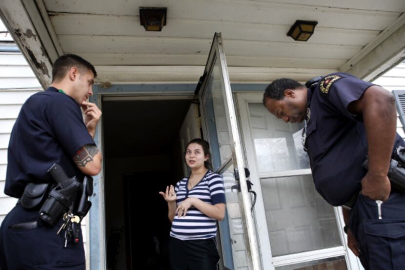 Officers Brandon Byrd (left) and Rory Jones (right) listen to Gabriela Popoca after...