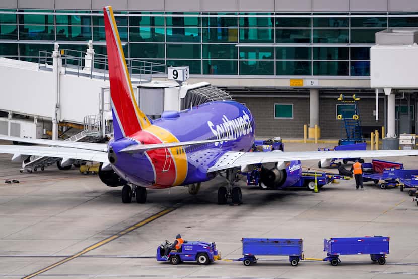 A worker drives baggage carts past a Southwest Airlines 737 at the gate at Dallas Love Field...