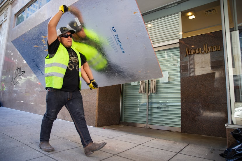 Crews work to board up the outside of Neiman Marcus after being hit during last night's...